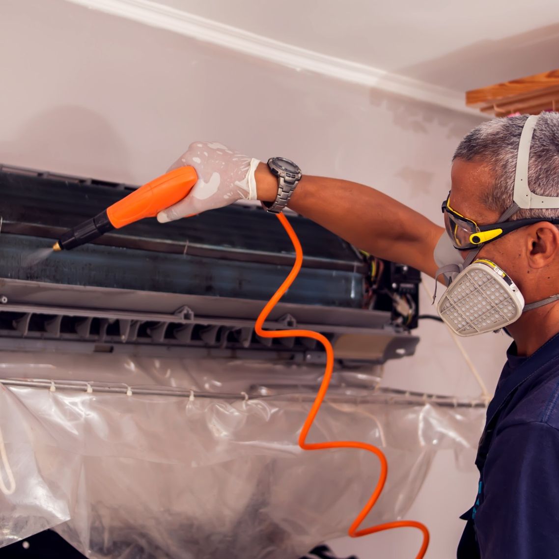 Picture of maintenance engineer deep cleaning a wall mounted air conditioning unit