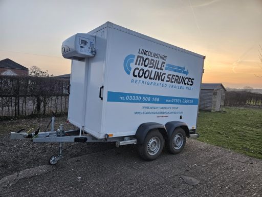 Mobile refrigerated trailer parked on gravel with a sunset in the background.