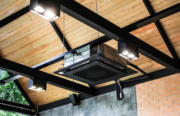 Exposed industrial look ceiling cassette painted black to match feature visible industrial style roof framework beams