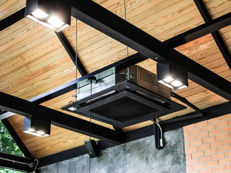 Exposed air conditioning cassette installation in black matching visible structral roof beams